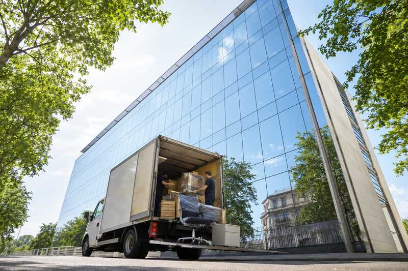 Chargement de mobilier professionnel devant un immeuble de bureaux