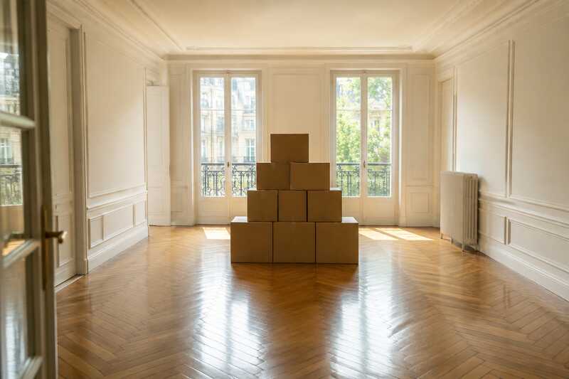 Pile de cartons fermés au centre d’un salon vidé