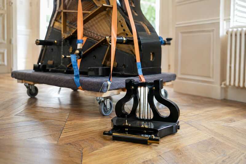 Piano à queue sur planche capitonnée, pieds et lyre démontés