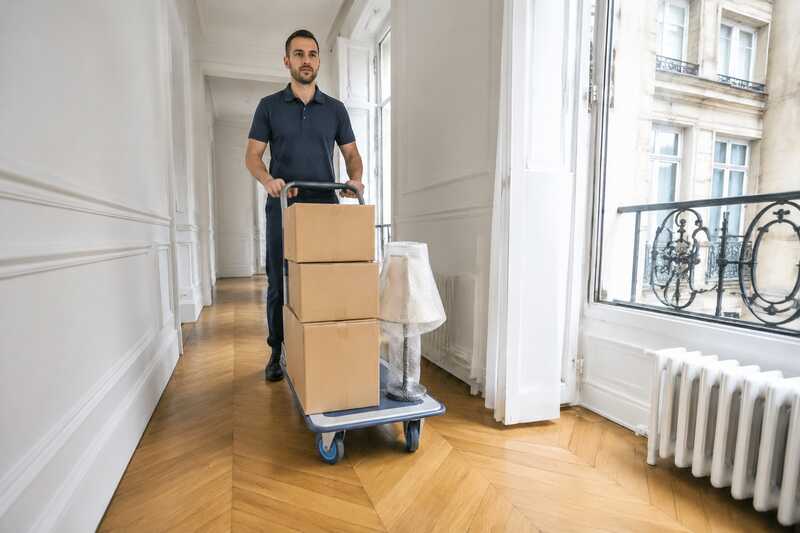 Chariot portant trois cartons et une lampe dans un couloir clair